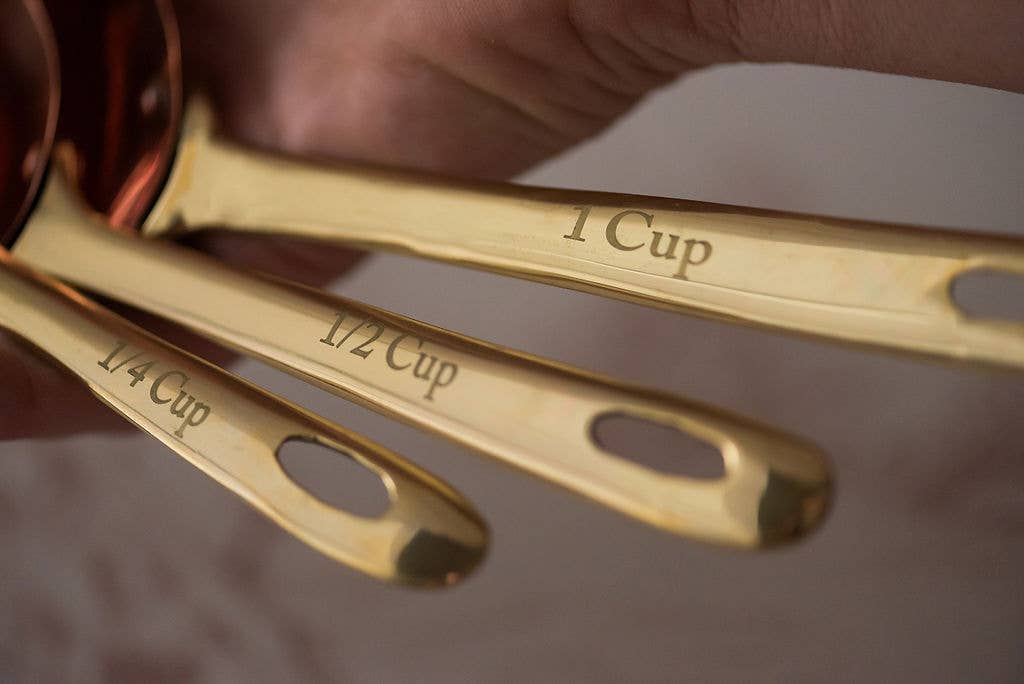 Set of gold measuring spoons with measurements engraved on them.