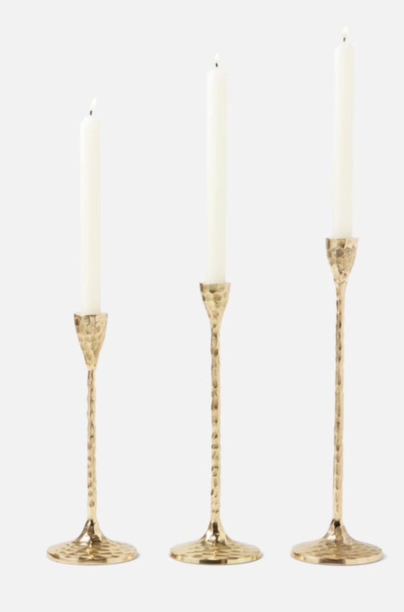 Three gold  hammered candle holders with candles on a white background